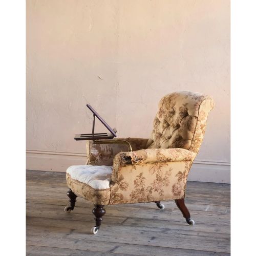 fig 1. A 19th-century Victorian library armchair upholstered in beige floral pattern fabric with deep buttoning, turned front legs on castors, and an attached adjustable mahogany reading stand.