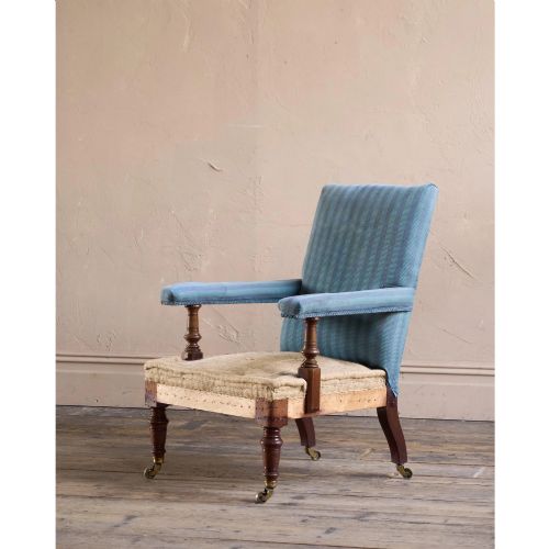 fig 1. A Victorian mahogany open armchair with turned front legs, brass castors, open padded arms, and blue striped fabric upholstery.