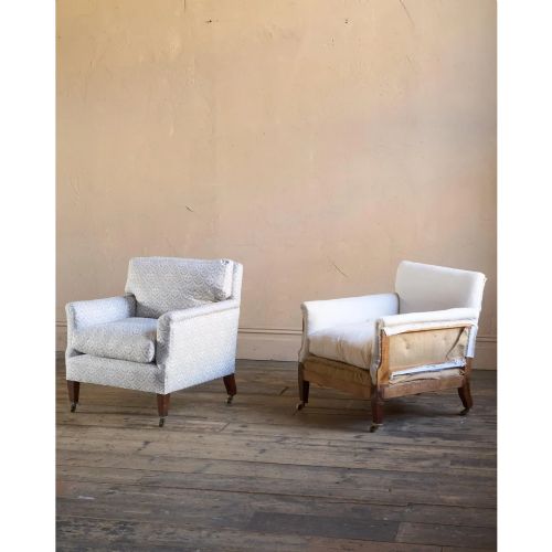 fig 1. A pair of low-slung Victorian armchairs with turned wooden front legs and brass castors, one upholstered in patterned fabric and one in white calico.