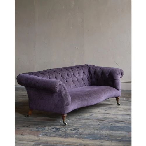 fig 1. A Victorian Chesterfield sofa featuring deep-buttoned floral pattern upholstery, rolled arms, and turned wooden legs fitted with brass castors.