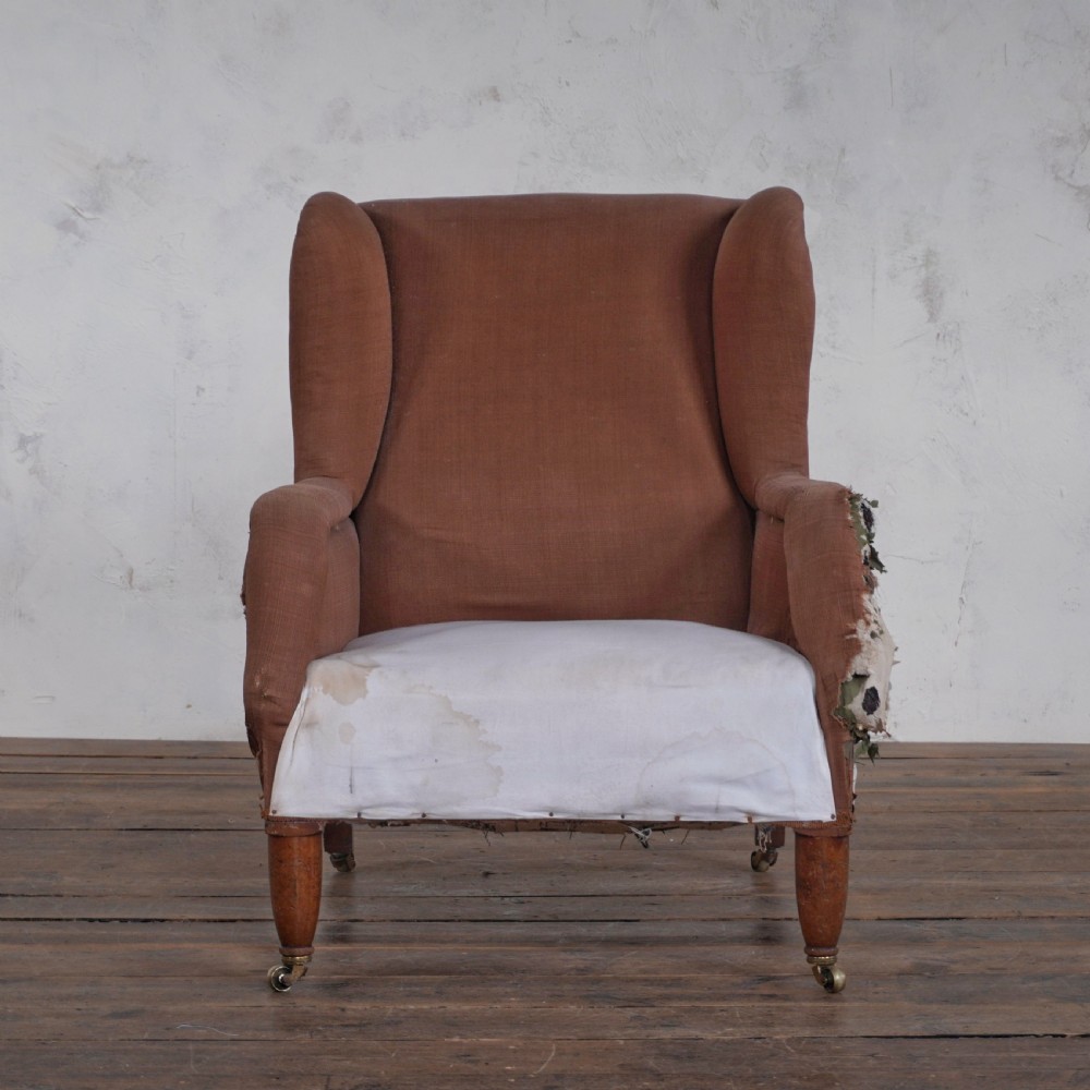 A Victorian wingback armchair upholstered in brown fabric and white calico with turned wood legs and brass castors. View II
