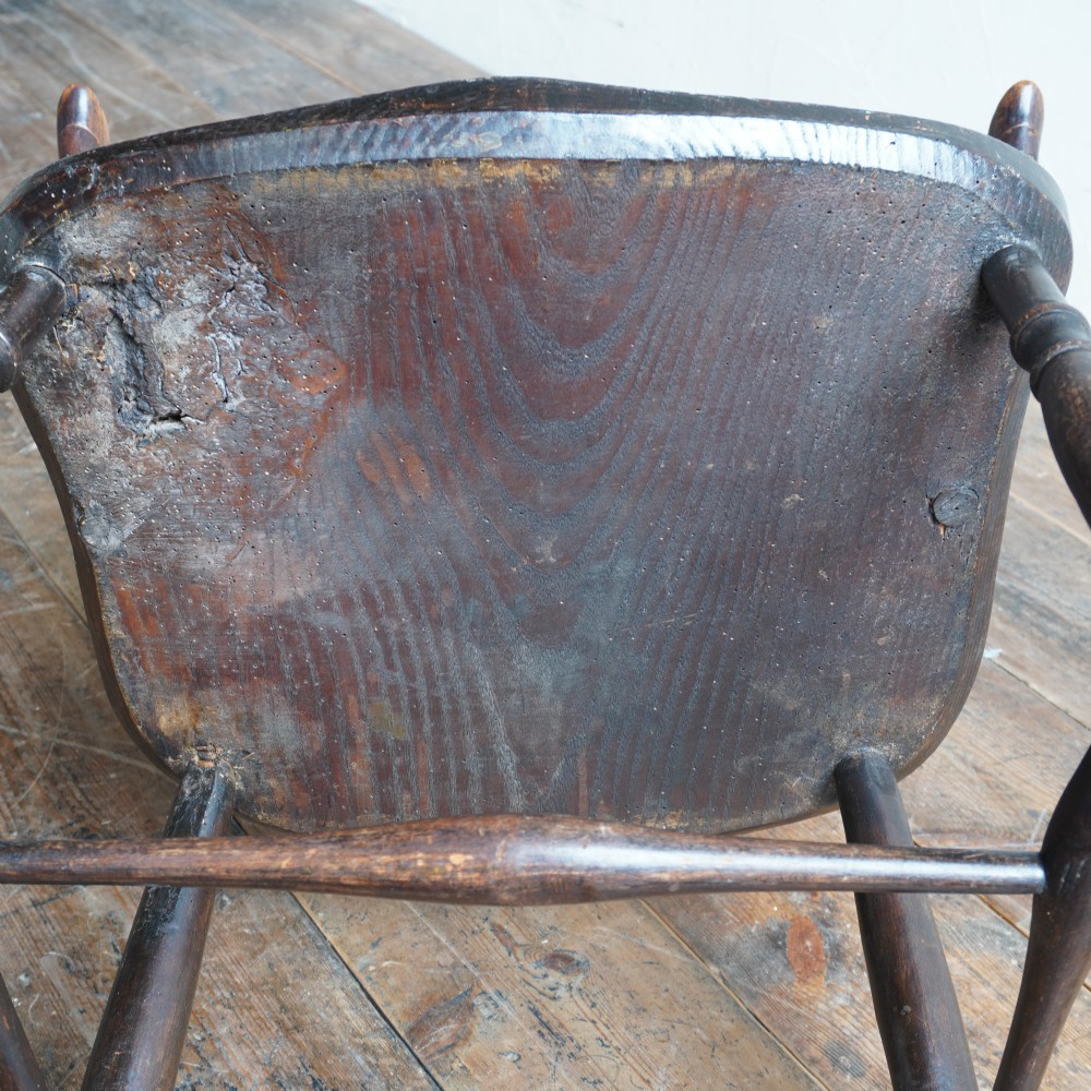 An antique dark wood comb back Windsor armchair with a saddle seat, slender vertical spindles, and turned legs joined by stretchers. View VII