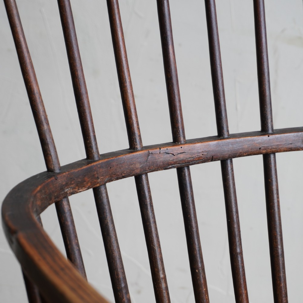 An antique dark wood comb back Windsor armchair with a saddle seat, slender vertical spindles, and turned legs joined by stretchers. View XIV