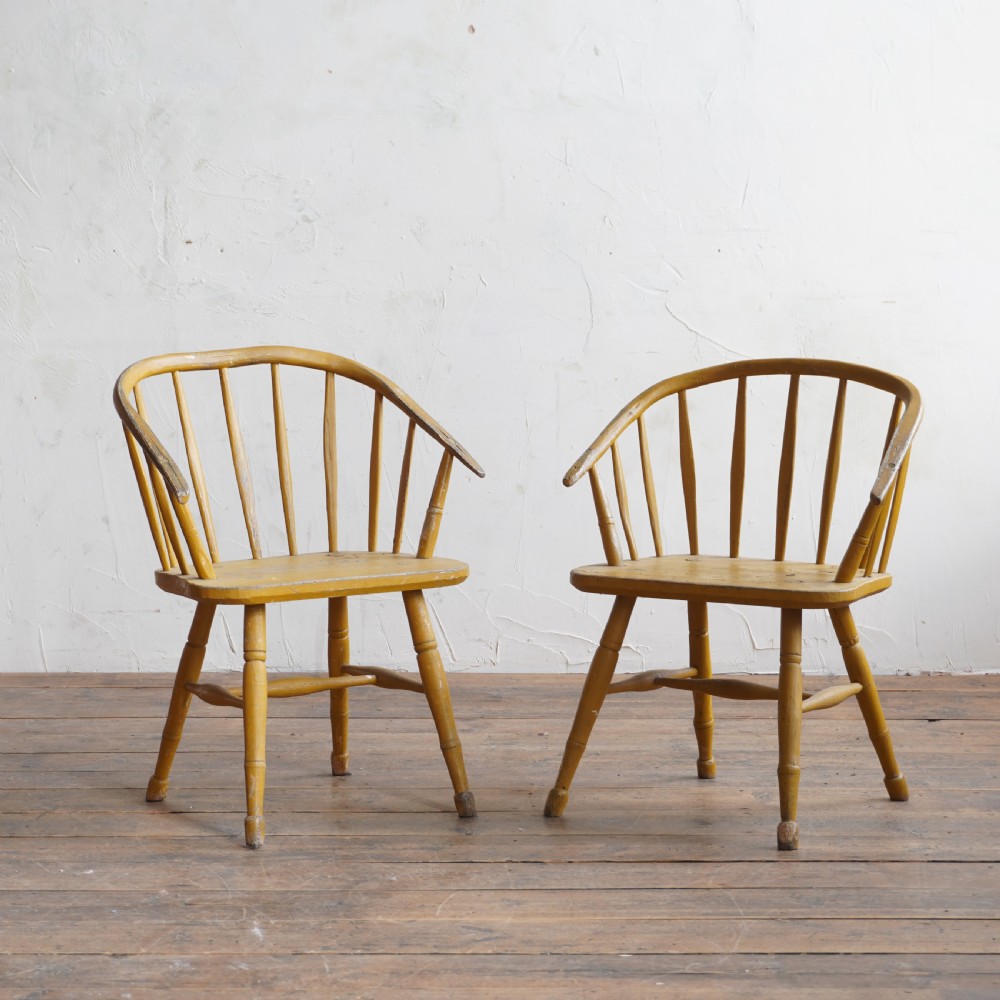 A pair of low-back wooden Windsor armchairs painted in a worn mustard yellow finish, featuring stick backs and turned legs. View VIII