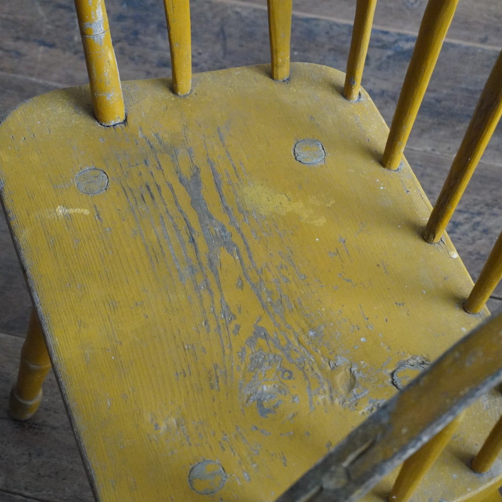A pair of low-back wooden Windsor armchairs painted in a worn mustard yellow finish, featuring stick backs and turned legs. View IX