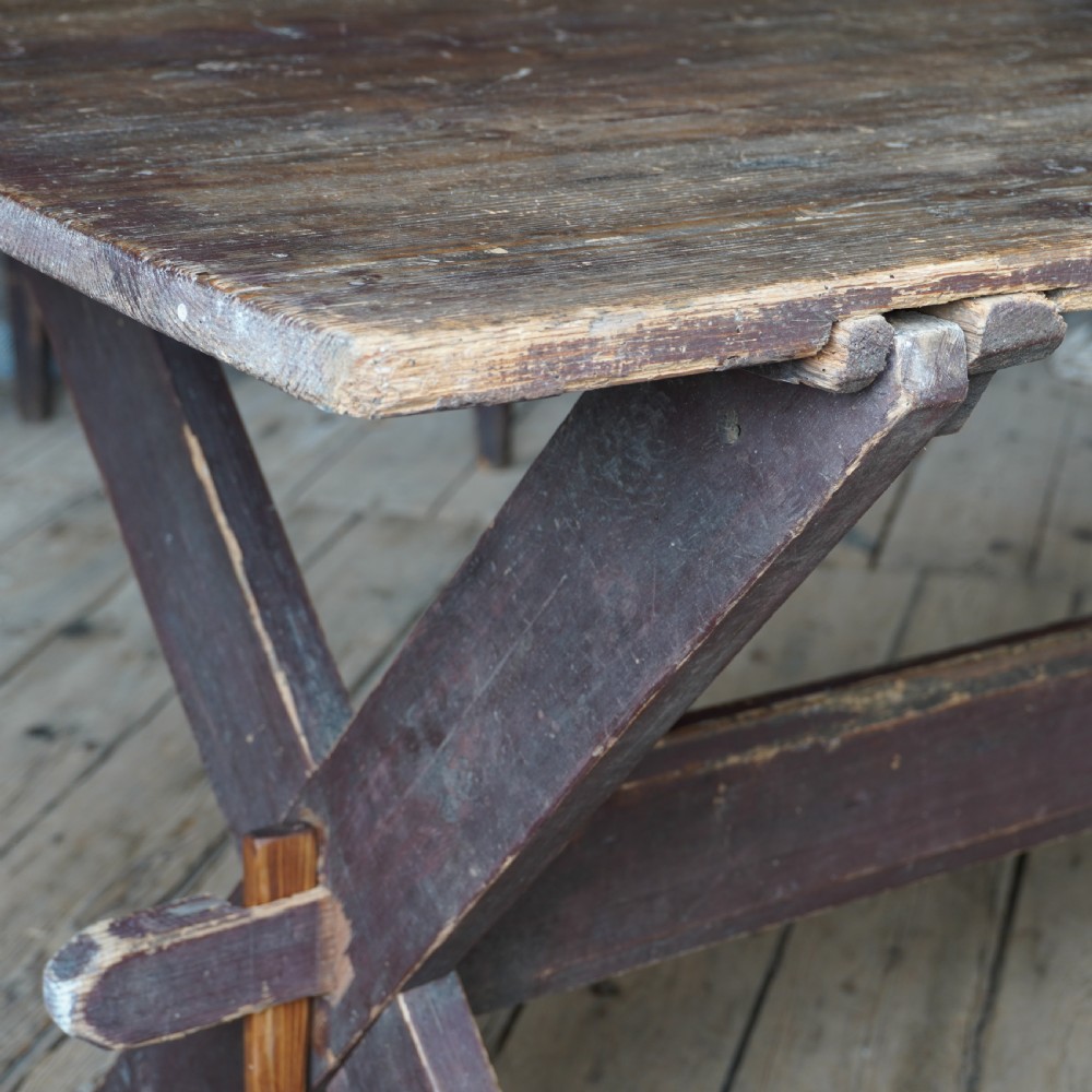 A rustic dark timber tavern table featuring an X-frame trestle base connected by a central horizontal stretcher. View VI
