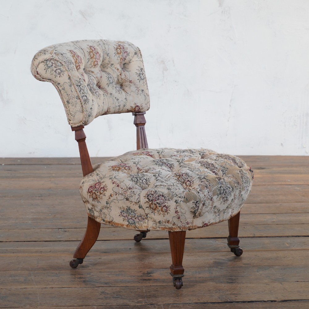 A Victorian low-seated slipper chair with deep-buttoned floral tapestry upholstery, supported by fluted front timber legs on brass castors. View II