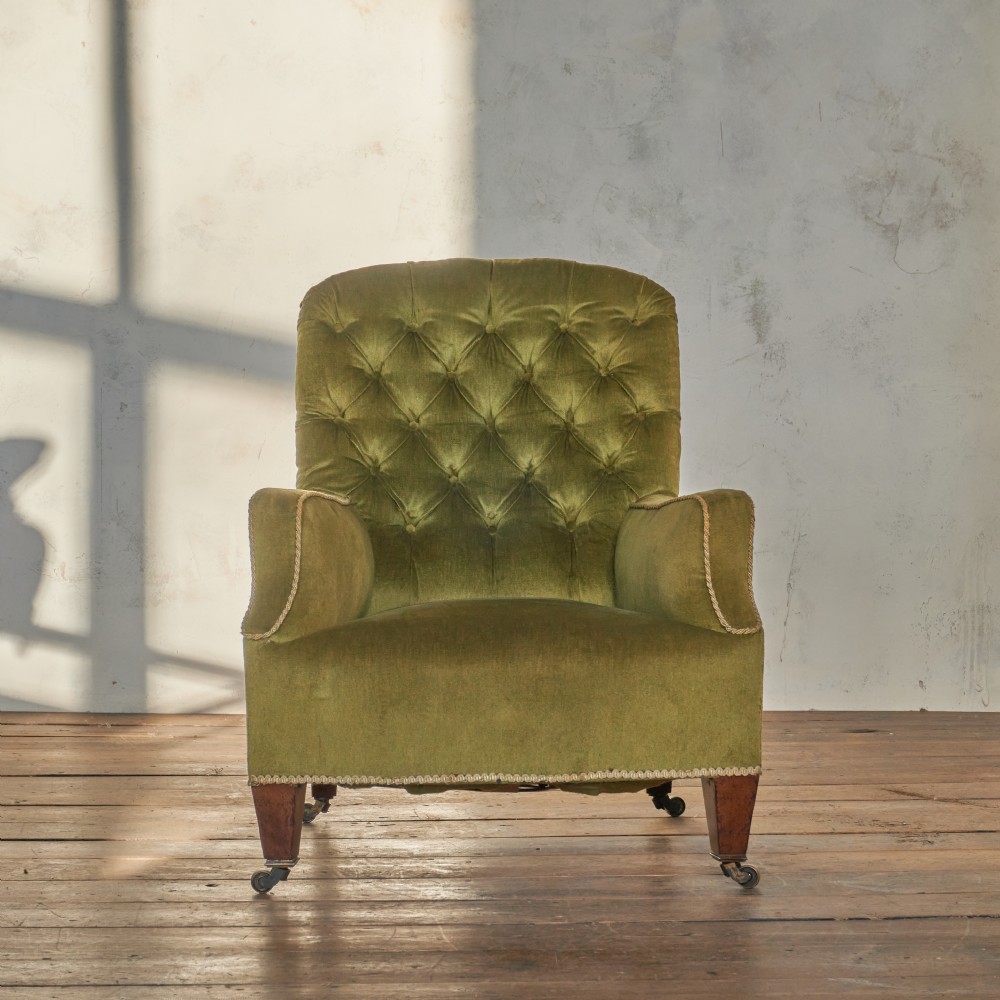 An antique armchair upholstered in green velvet with button-tufted backrest and turned wooden legs on brass castors. View VIII