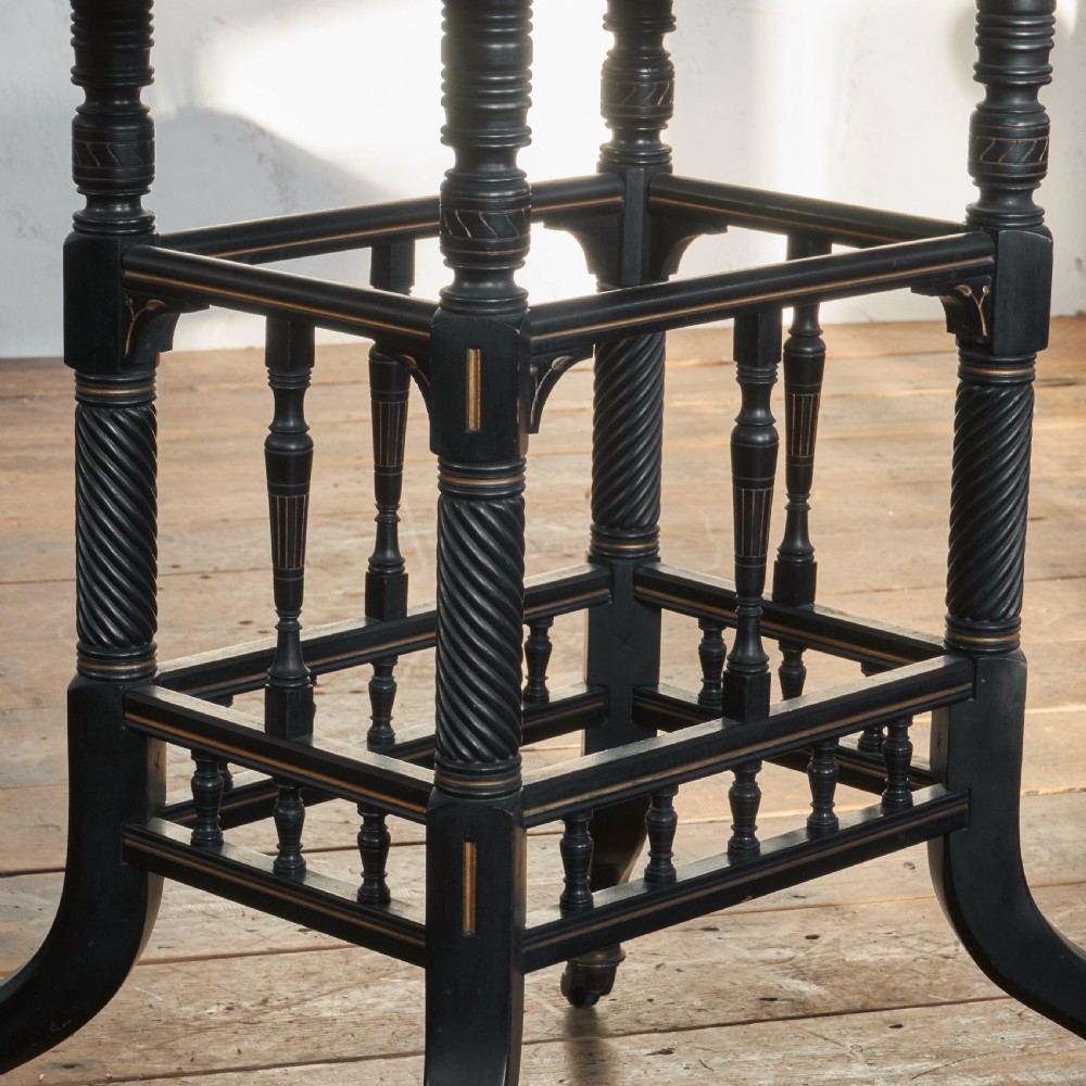 An ebonised late Victorian Aesthetic Movement card table with a rectangular fold-over top, incised gilt accents, spiral-turned legs, a lower spindle shelf, and brass castors. View VIII