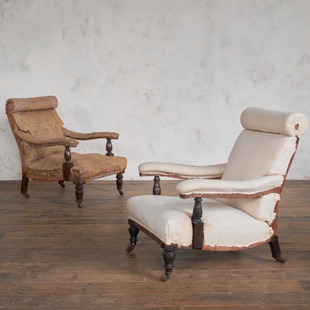A matched pair of antique open armchairs featuring exposed wooden frames, turned legs with castors, and bolster head rolls. View II