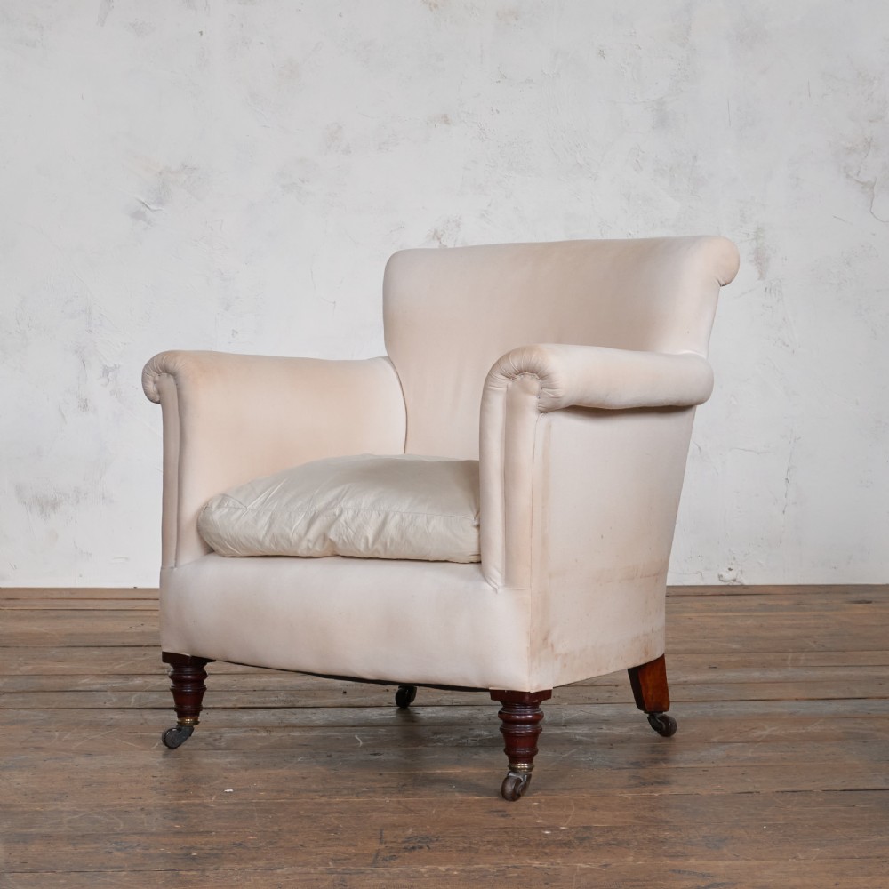 An antique cream calico upholstered tub chair featuring rolled arms, a loose seat cushion, and turned mahogany legs on brass castors. View II