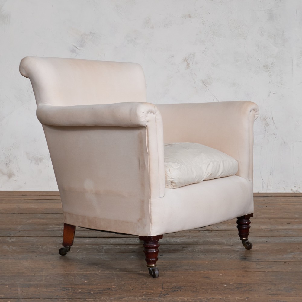 An antique cream calico upholstered tub chair featuring rolled arms, a loose seat cushion, and turned mahogany legs on brass castors. View III