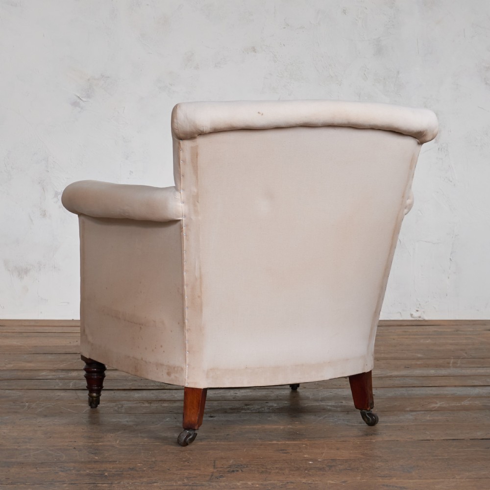 An antique cream calico upholstered tub chair featuring rolled arms, a loose seat cushion, and turned mahogany legs on brass castors. View IV