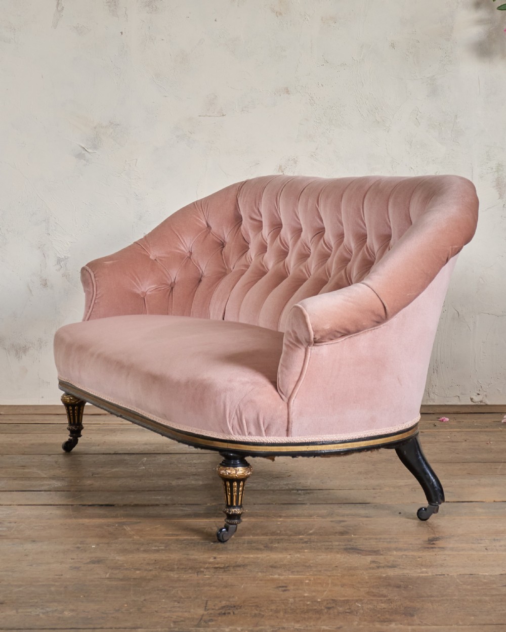 An antique Aesthetic Movement sofa upholstered in pink velvet, featuring ebonised and gilded carved legs on castors. View IV