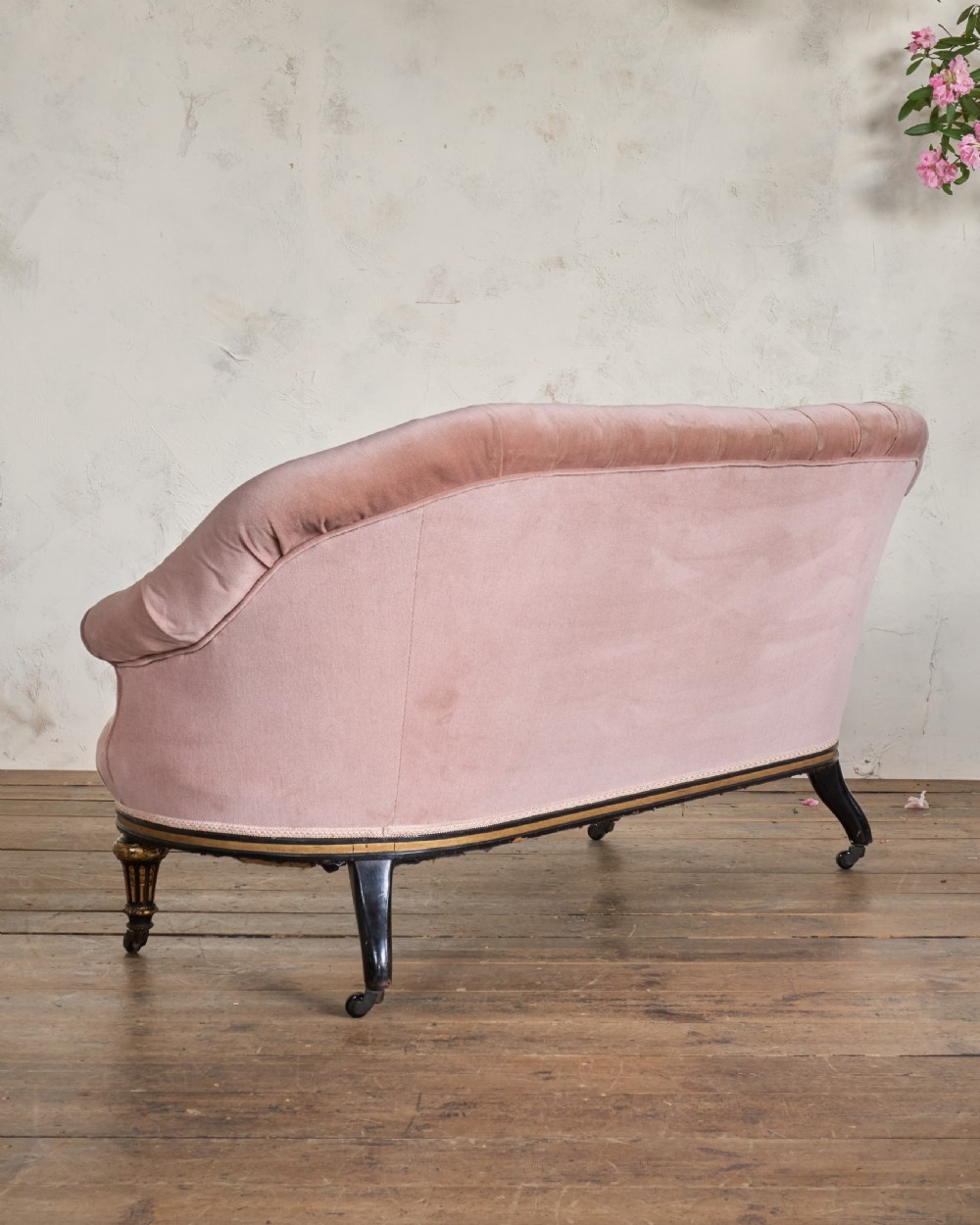 An antique Aesthetic Movement sofa upholstered in pink velvet, featuring ebonised and gilded carved legs on castors. View V