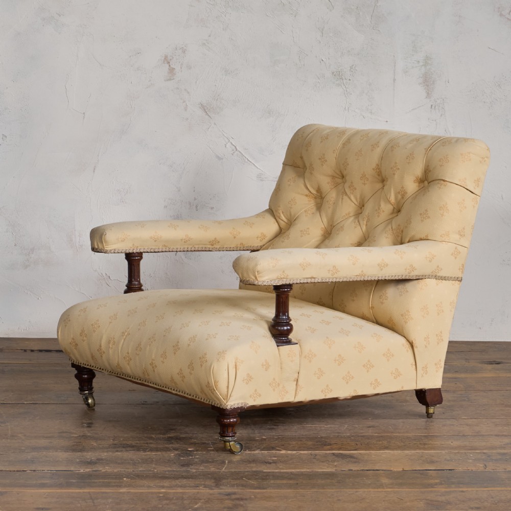 A Victorian open armchair upholstered in gold patterned fabric with a deep buttoned backrest, padded open arms on turned wood supports, and turned wooden legs fitted with brass castors.