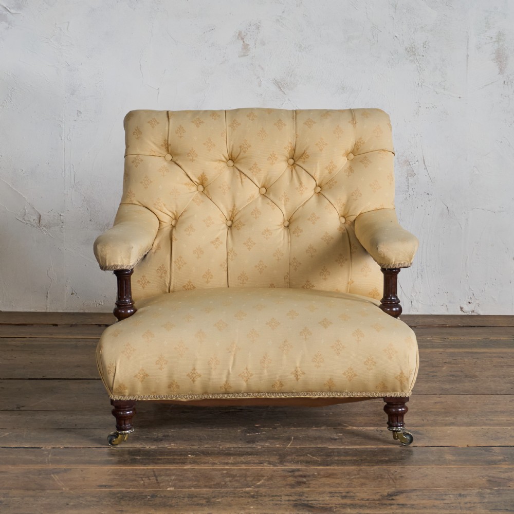 A Victorian open armchair upholstered in gold patterned fabric with a deep buttoned backrest, padded open arms on turned wood supports, and turned wooden legs fitted with brass castors. View II