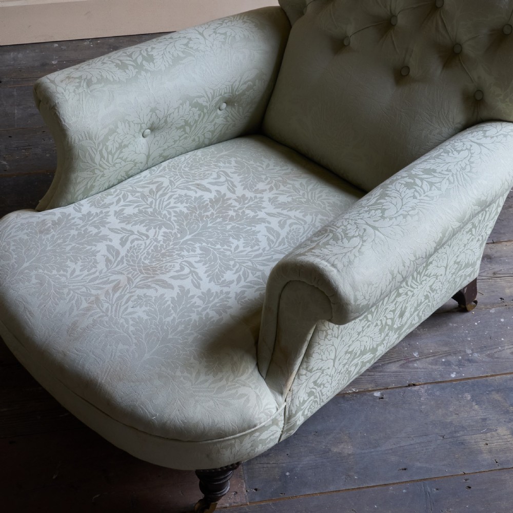 An antique sage green damask upholstered armchair with rolled arms, button tufting, and turned wooden legs with brass castors. View VII