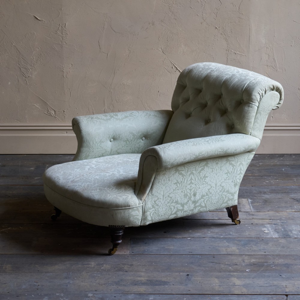 An antique sage green damask upholstered armchair with rolled arms, button tufting, and turned wooden legs with brass castors. View II
