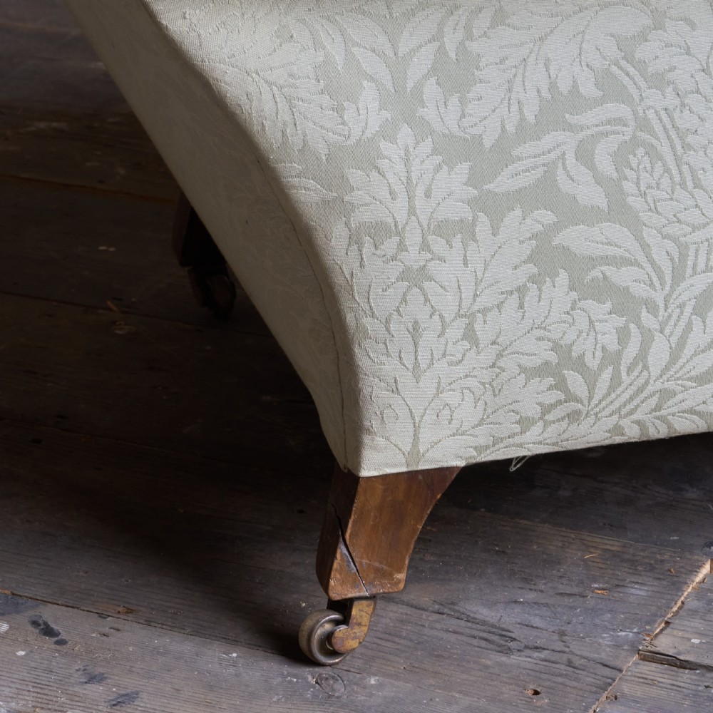 An antique sage green damask upholstered armchair with rolled arms, button tufting, and turned wooden legs with brass castors. View III