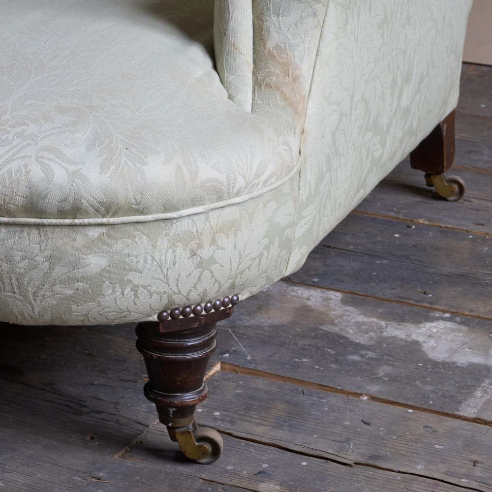 An antique sage green damask upholstered armchair with rolled arms, button tufting, and turned wooden legs with brass castors. View IV