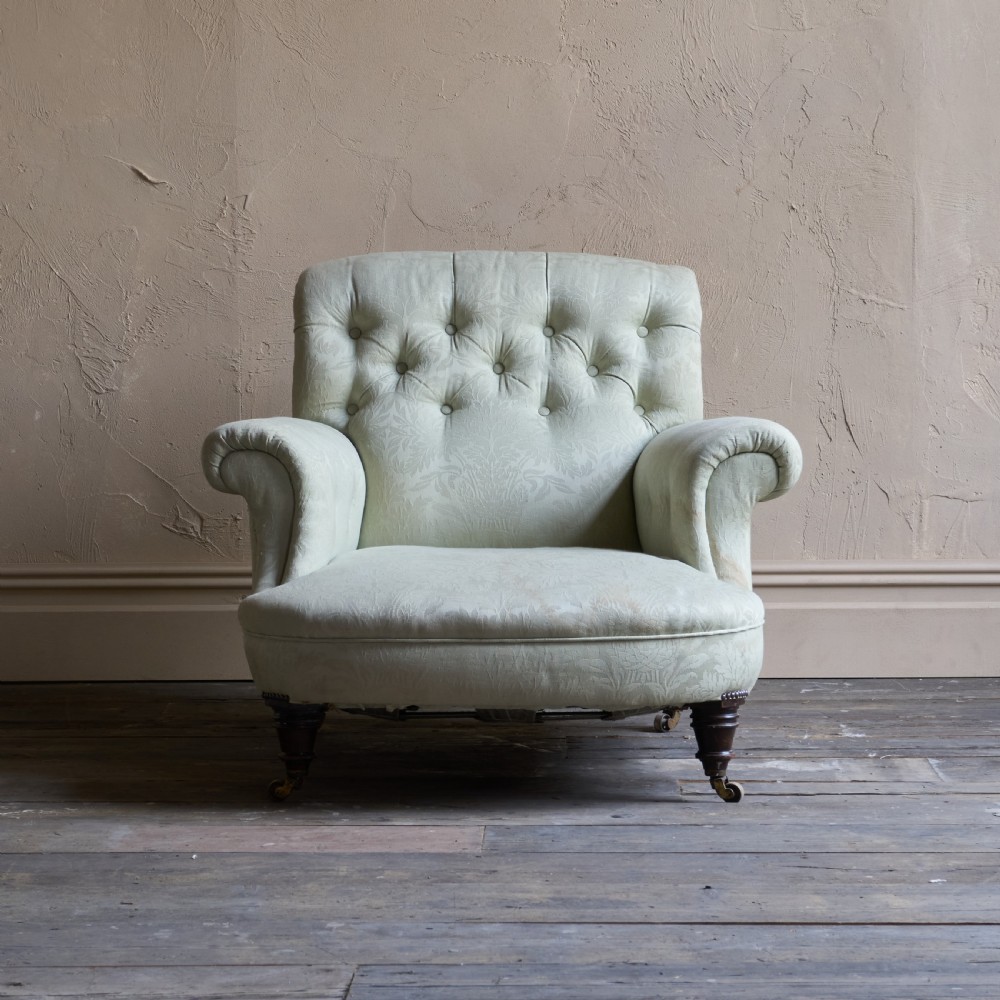An antique sage green damask upholstered armchair with rolled arms, button tufting, and turned wooden legs with brass castors. View V