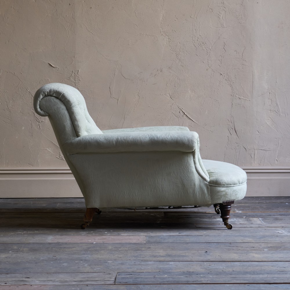 An antique sage green damask upholstered armchair with rolled arms, button tufting, and turned wooden legs with brass castors. View VI