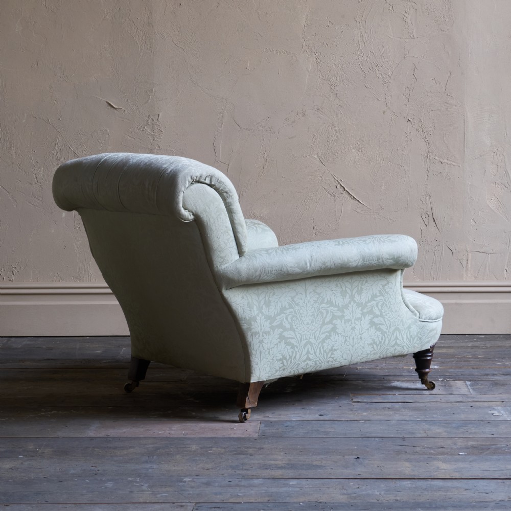 An antique sage green damask upholstered armchair with rolled arms, button tufting, and turned wooden legs with brass castors. View VIII