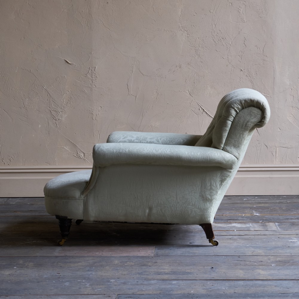 An antique sage green damask upholstered armchair with rolled arms, button tufting, and turned wooden legs with brass castors. View IX