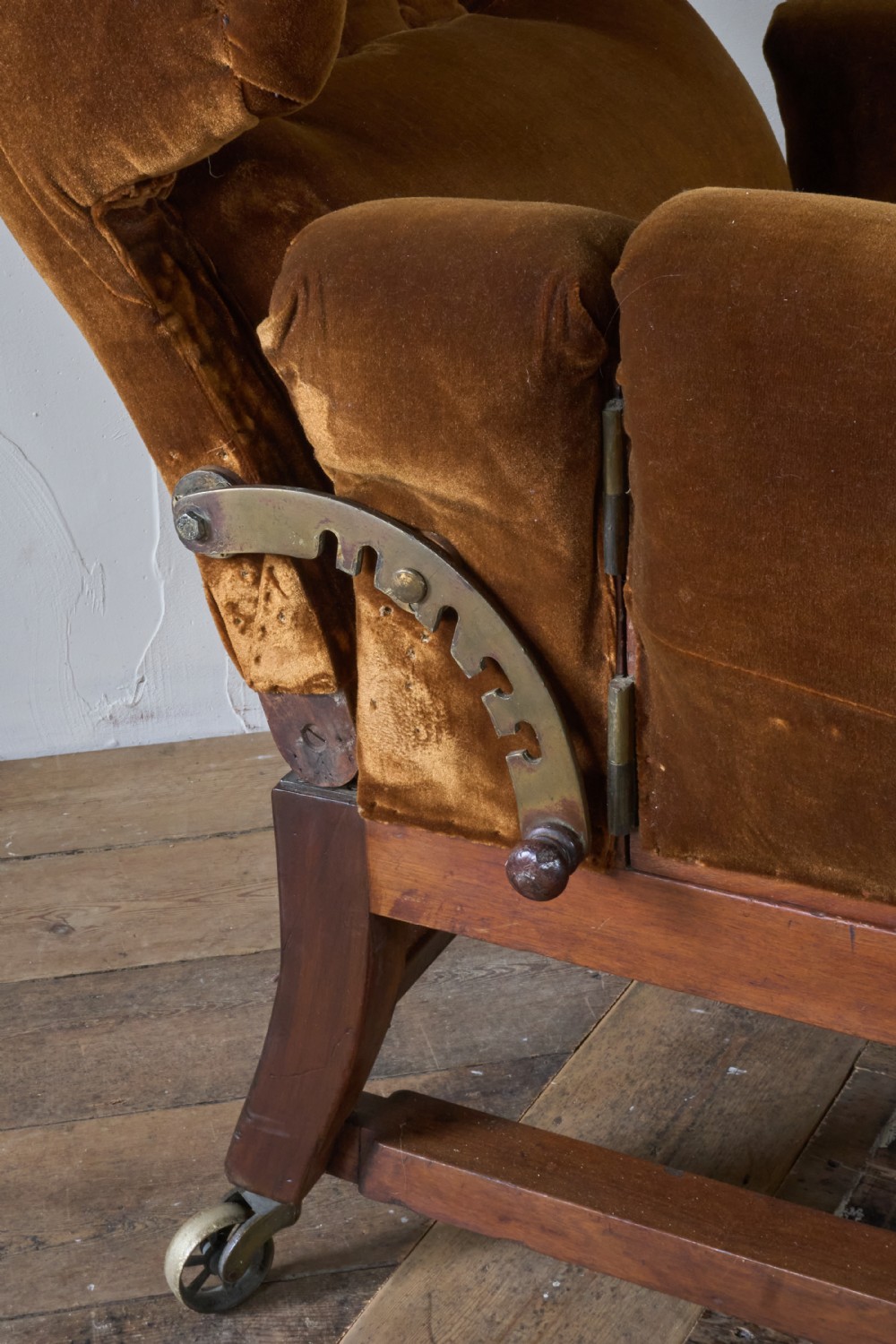 An antique Victorian mechanical reclining armchair upholstered in brown velvet with a button-tufted backrest, padded armrests, and an extendable footrest on brass castors. View VI
