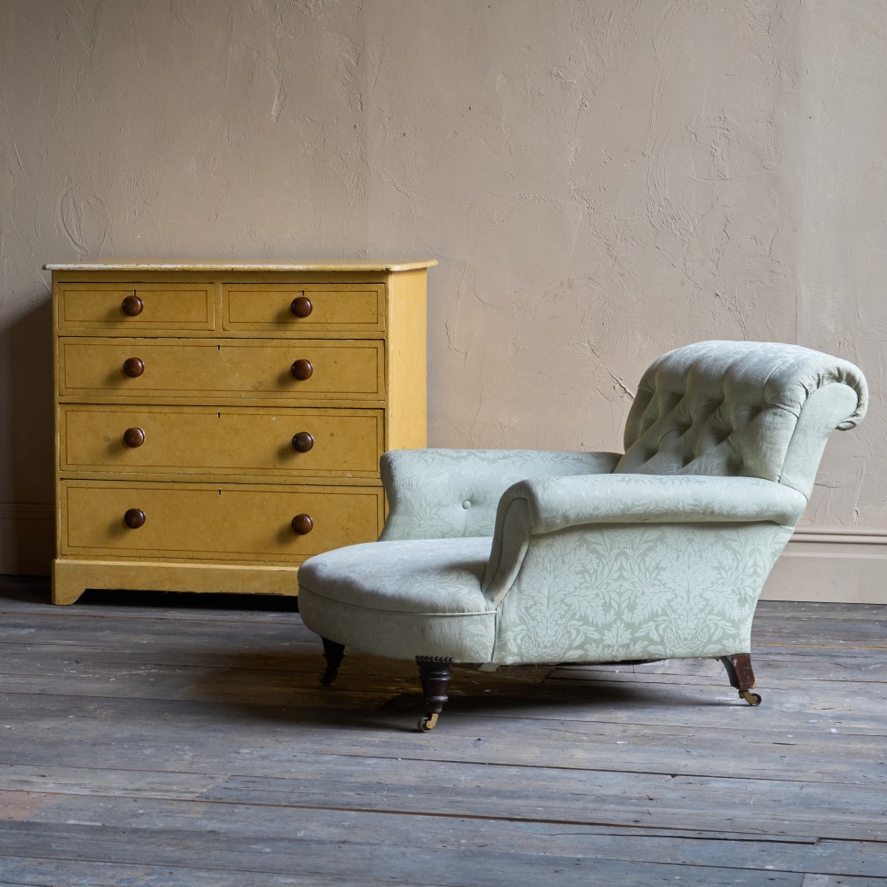 An antique sage green damask upholstered armchair with rolled arms, button tufting, and turned wooden legs with brass castors. View XI