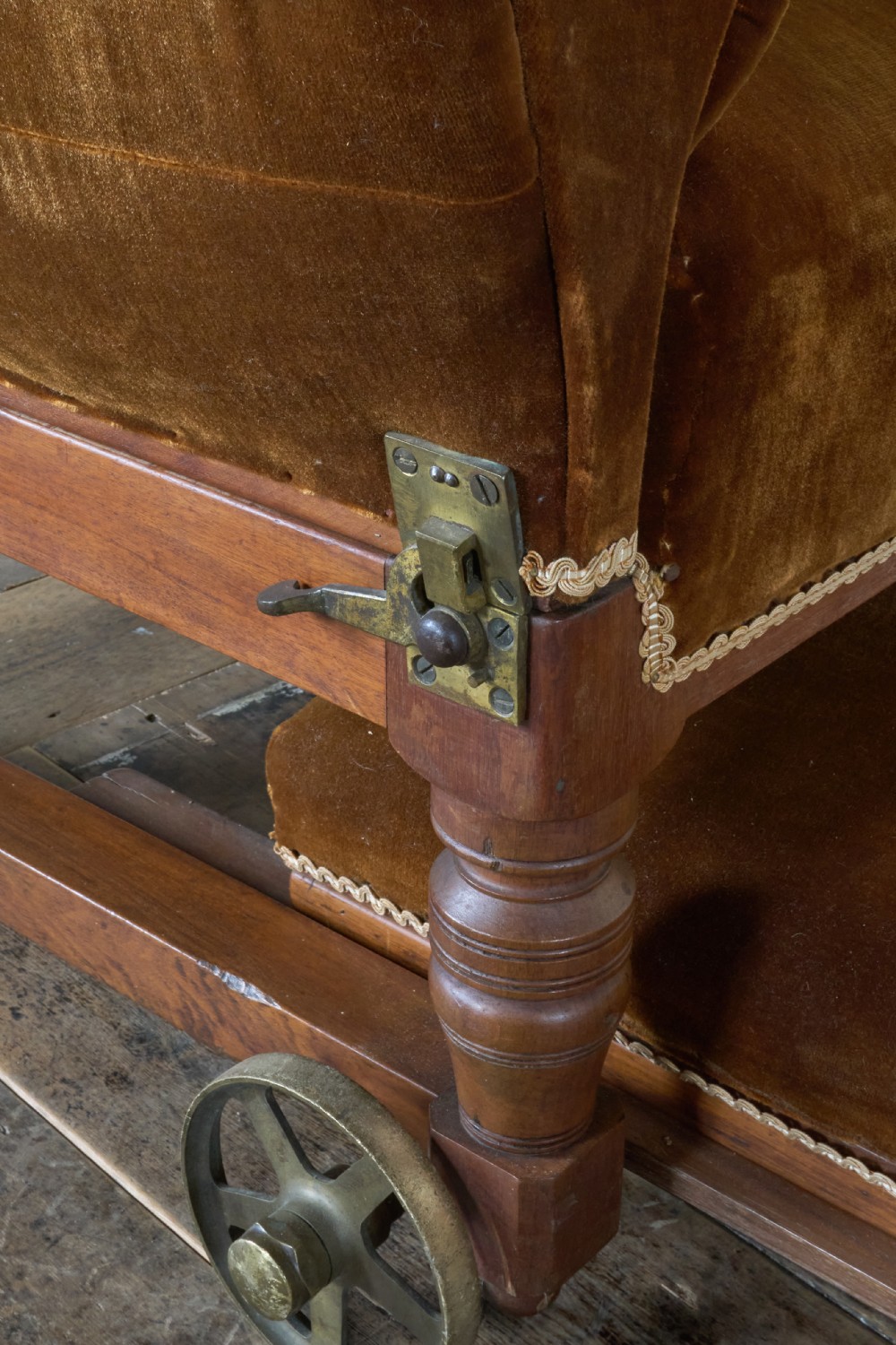 An antique Victorian mechanical reclining armchair upholstered in brown velvet with a button-tufted backrest, padded armrests, and an extendable footrest on brass castors. View VII