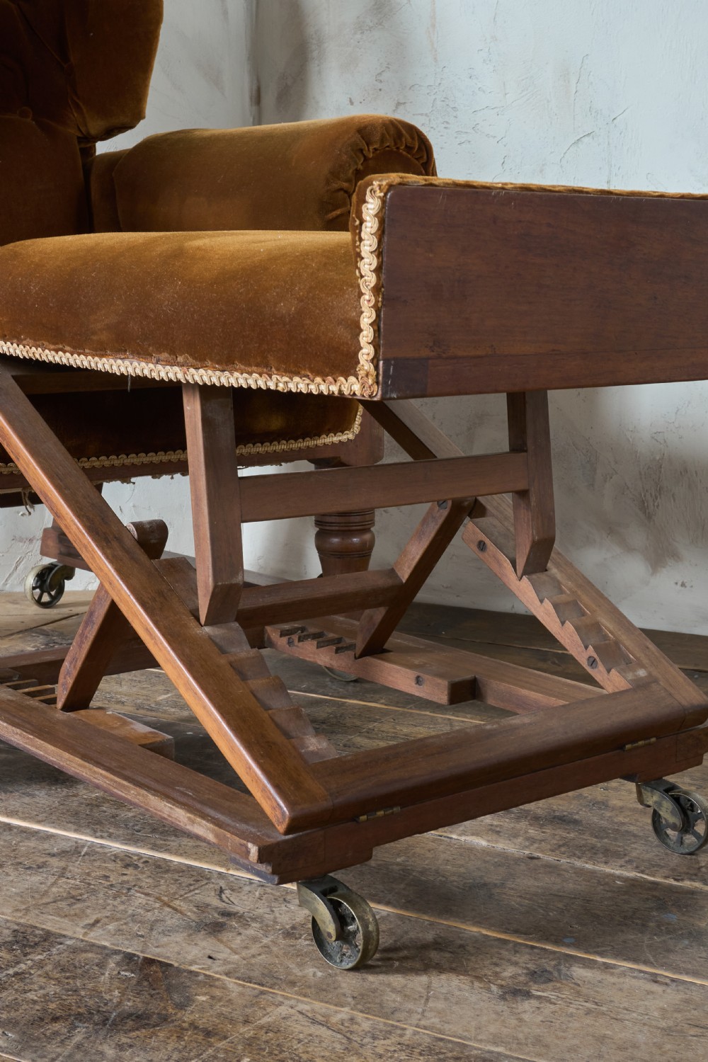 An antique Victorian mechanical reclining armchair upholstered in brown velvet with a button-tufted backrest, padded armrests, and an extendable footrest on brass castors. View IX