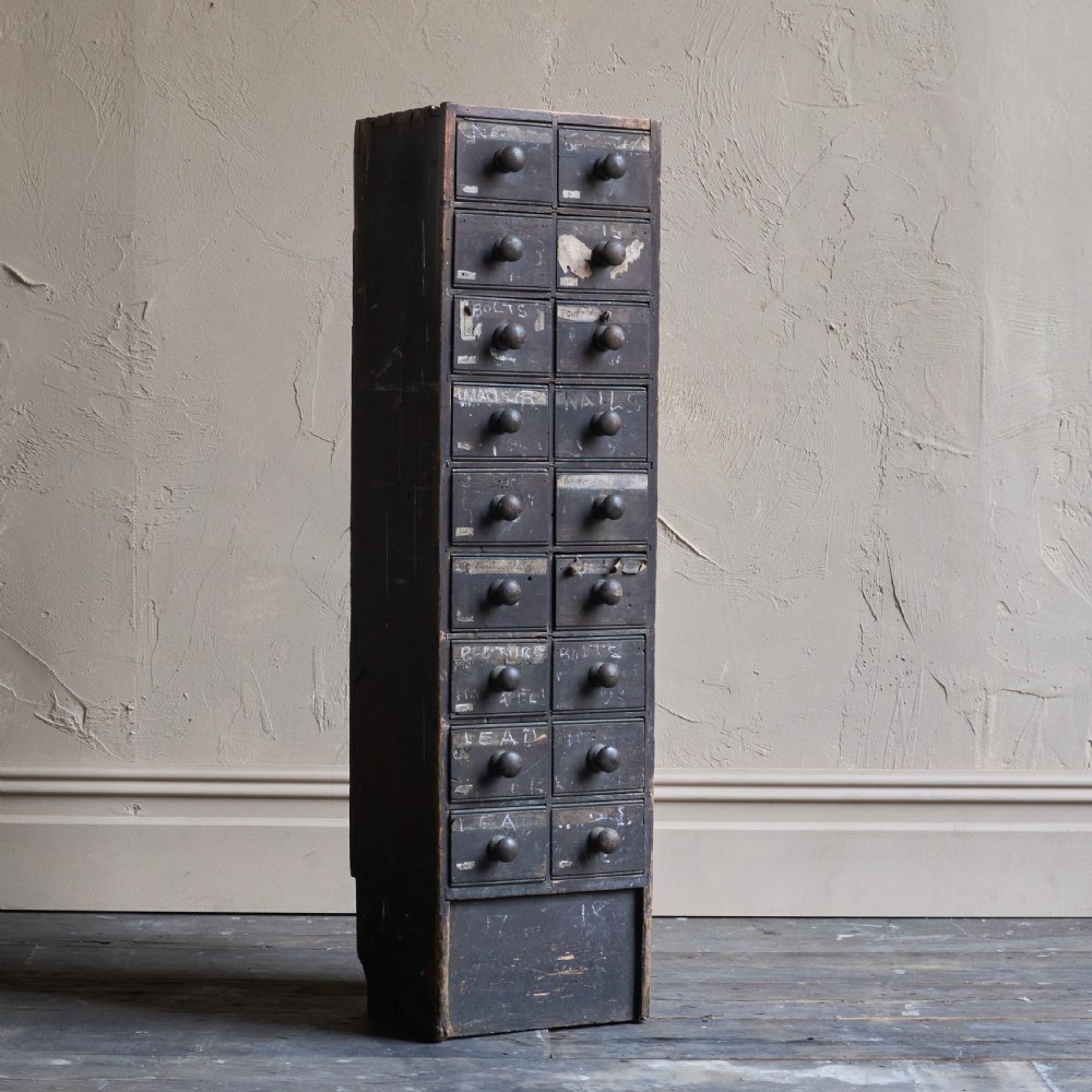 A tall and narrow antique dark wood ironmongers chest featuring sixteen small drawers with turned knobs and hand-painted white labels. View II