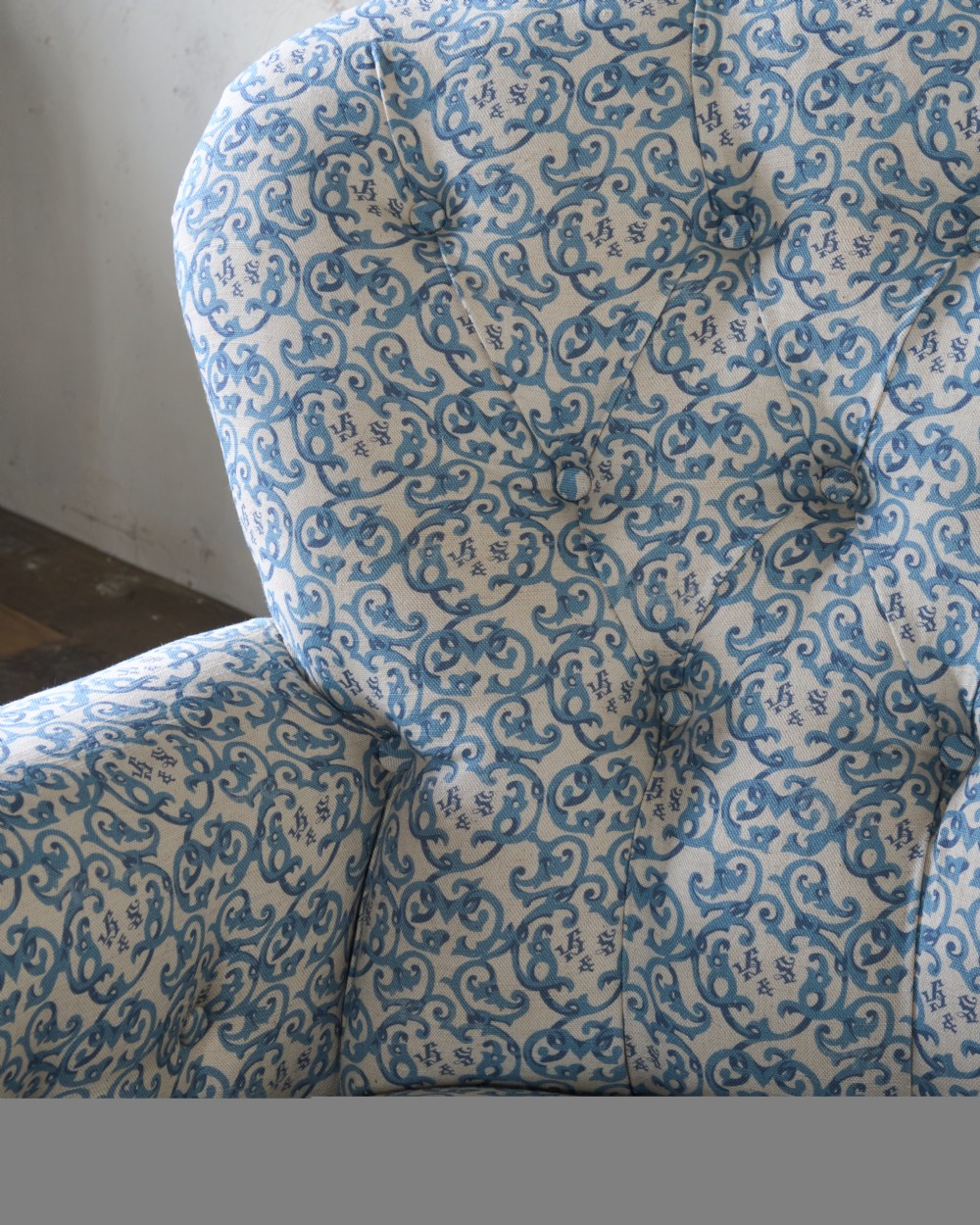 A Victorian Howard style armchair upholstered in blue and white scroll printed fabric with deep buttoning and turned mahogany legs on brass castors. View VII