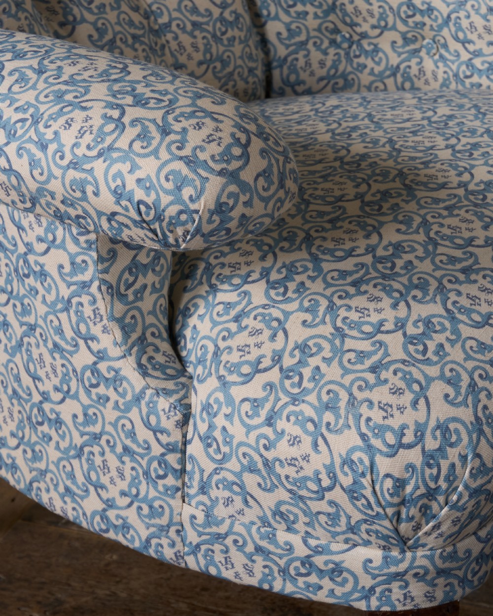 A Victorian Howard style armchair upholstered in blue and white scroll printed fabric with deep buttoning and turned mahogany legs on brass castors. View VIII
