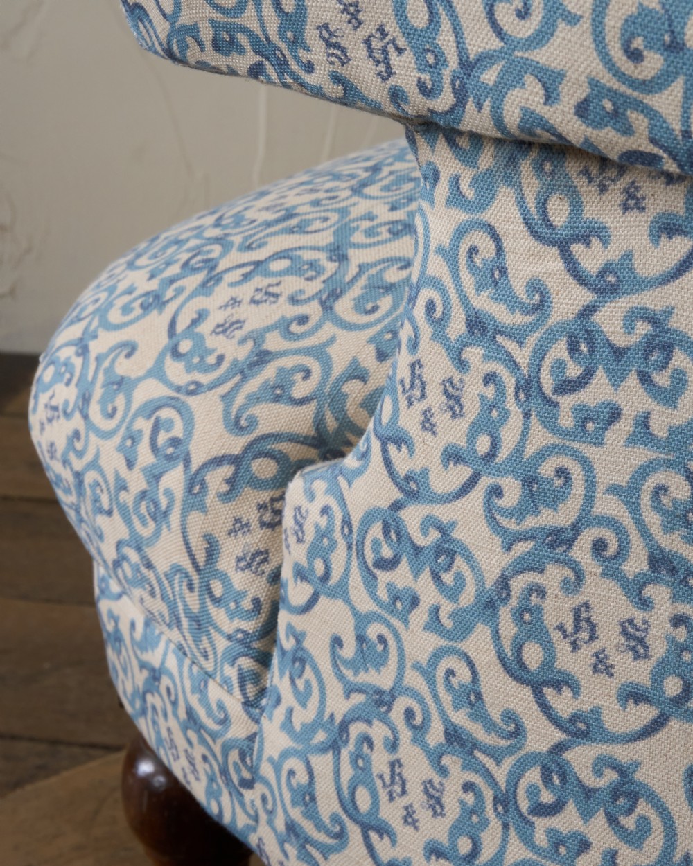 A Victorian Howard style armchair upholstered in blue and white scroll printed fabric with deep buttoning and turned mahogany legs on brass castors. View XIII