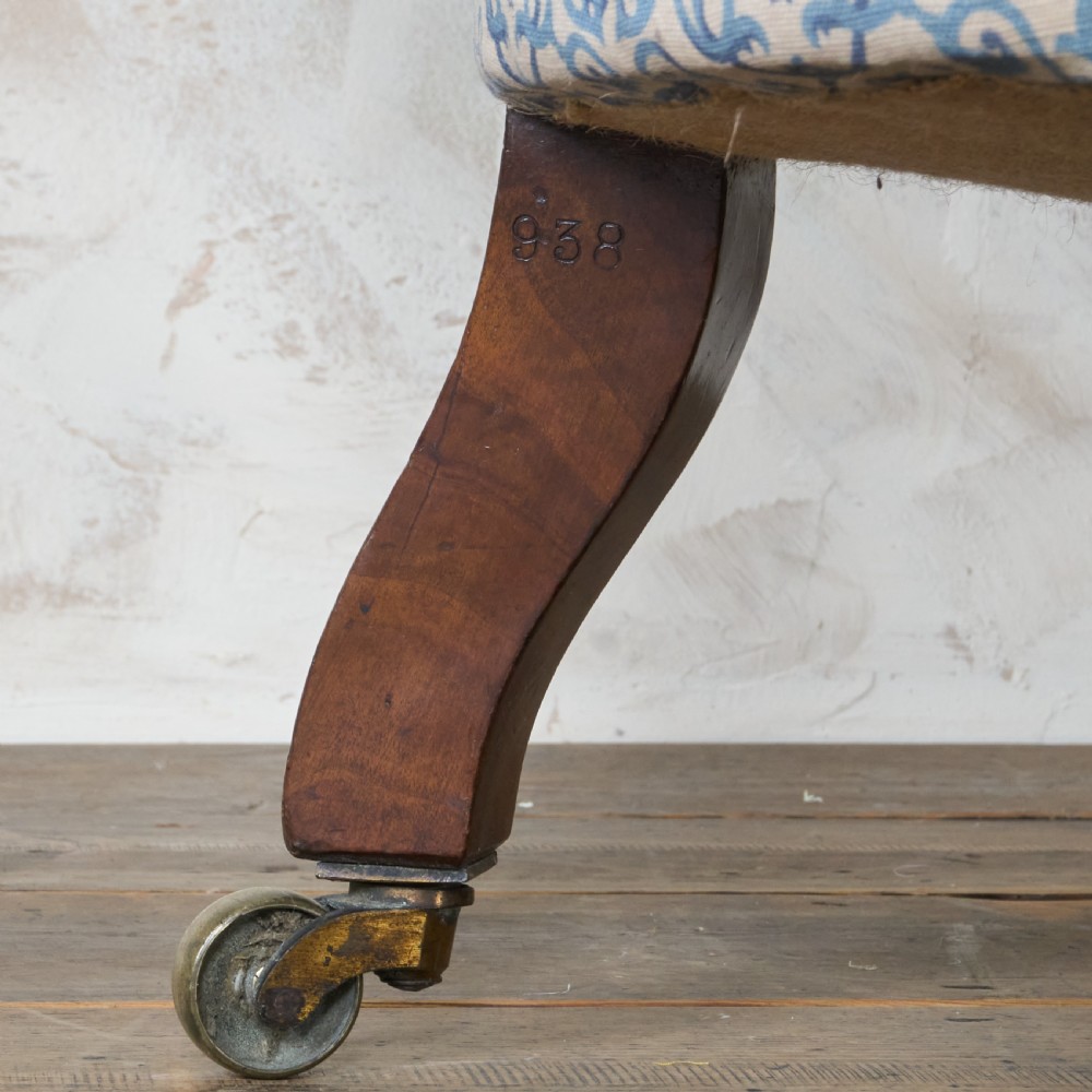 A Victorian Howard style armchair upholstered in blue and white scroll printed fabric with deep buttoning and turned mahogany legs on brass castors. View XIV