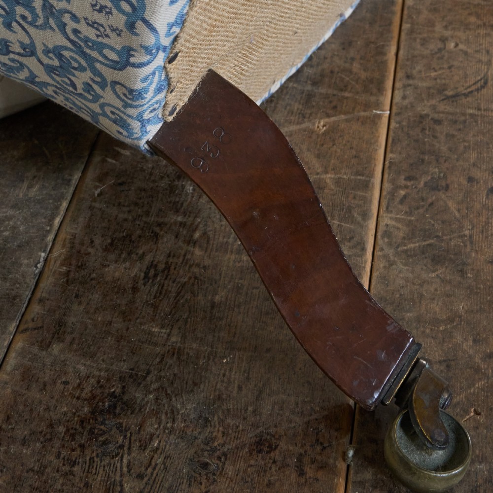 A Victorian Howard style armchair upholstered in blue and white scroll printed fabric with deep buttoning and turned mahogany legs on brass castors. View XV