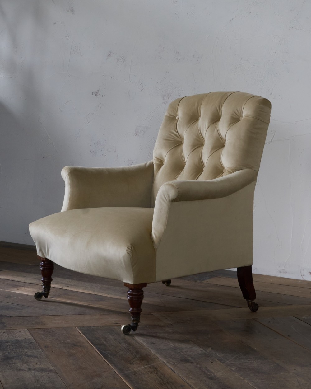 A deep-seated Victorian armchair upholstered in gold velvet with a button-backed backrest, turned mahogany front legs, and brass castors. View III
