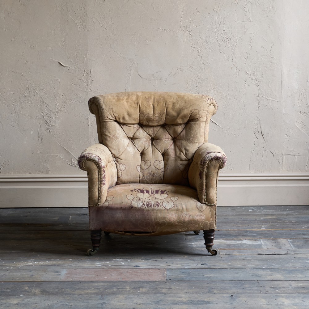 A low-seated Victorian style upholstered easy chair featuring a deep-buttoned backrest, rolled arms, floral damask pattern, and turned timber front legs with brass castors. View III
