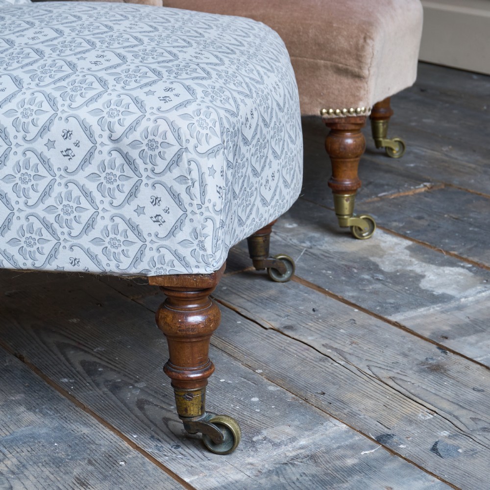 A pair of Victorian low-slung button-backed slipper chairs with turned wooden legs on brass castors, one in taupe velvet and one in patterned blue and white fabric. View III
