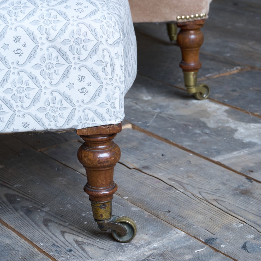 A pair of Victorian low-slung button-backed slipper chairs with turned wooden legs on brass castors, one in taupe velvet and one in patterned blue and white fabric. View VII