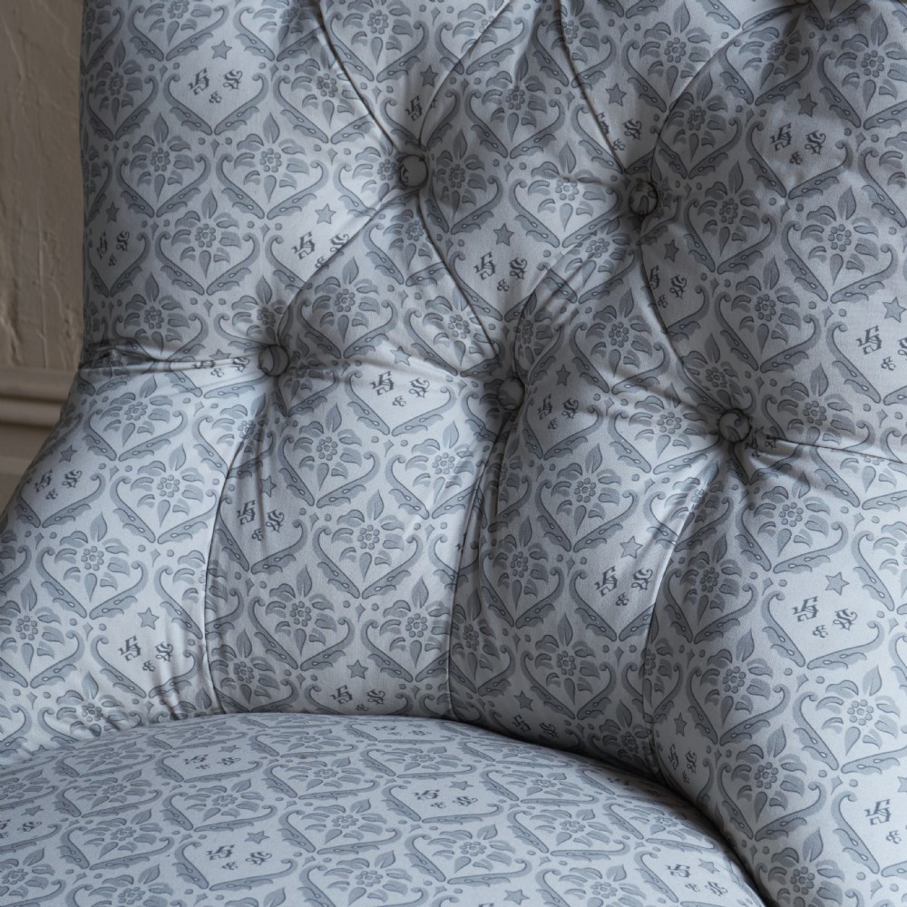 A pair of Victorian low-slung button-backed slipper chairs with turned wooden legs on brass castors, one in taupe velvet and one in patterned blue and white fabric. View VIII