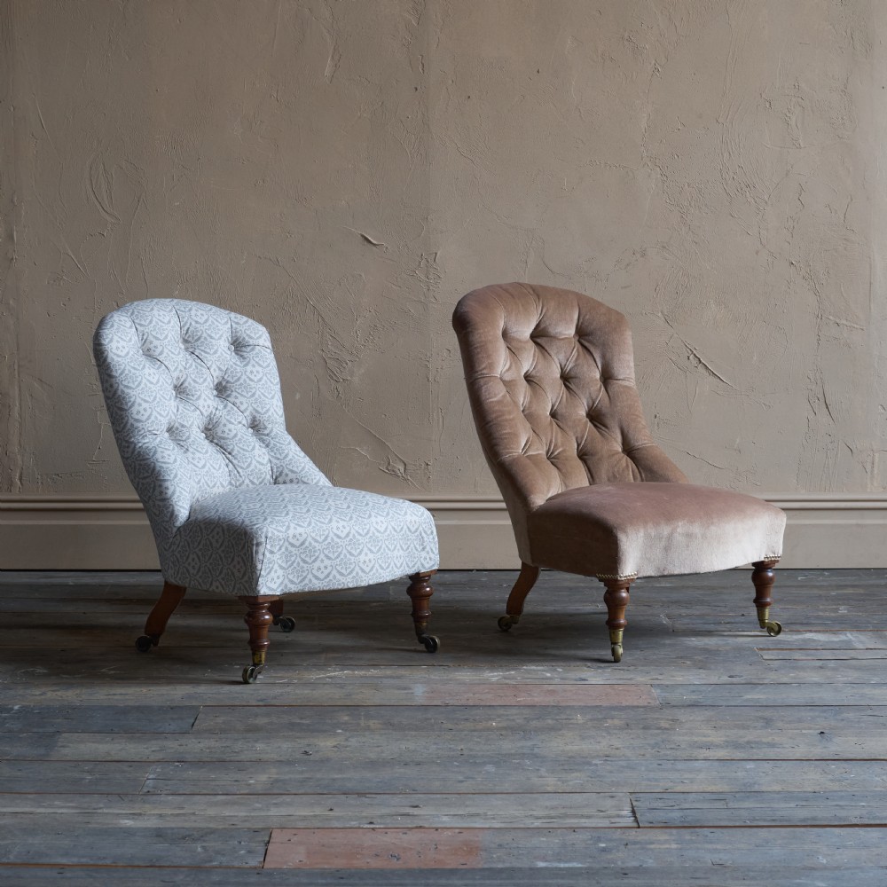 A pair of Victorian low-slung button-backed slipper chairs with turned wooden legs on brass castors, one in taupe velvet and one in patterned blue and white fabric. View XI
