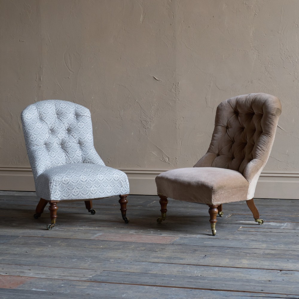 A pair of Victorian low-slung button-backed slipper chairs with turned wooden legs on brass castors, one in taupe velvet and one in patterned blue and white fabric. View XII