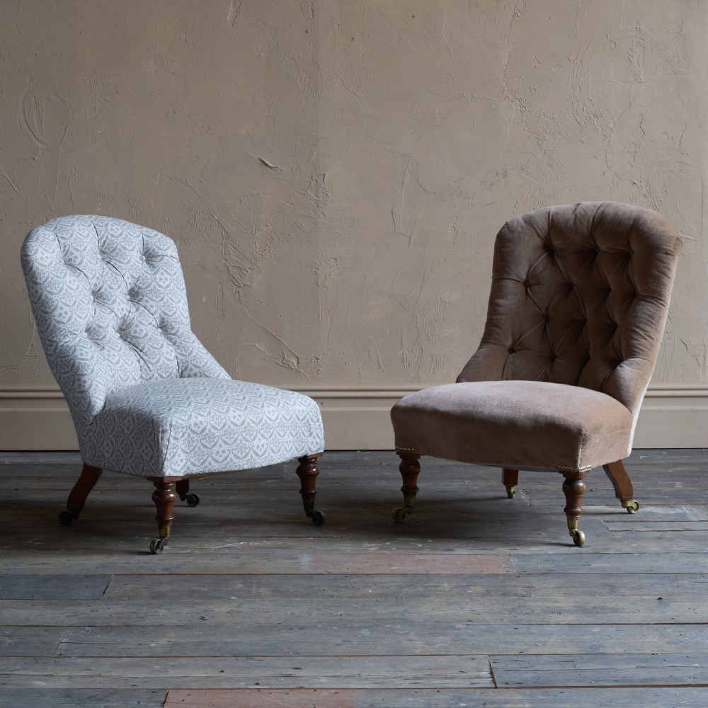A pair of Victorian low-slung button-backed slipper chairs with turned wooden legs on brass castors, one in taupe velvet and one in patterned blue and white fabric. View XIII