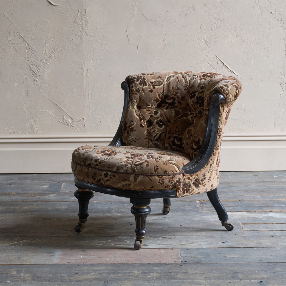 A Victorian low-seated tub chair upholstered in brown patterned floral velvet with ebonised turned legs, gilt accents, and brass castors. View III