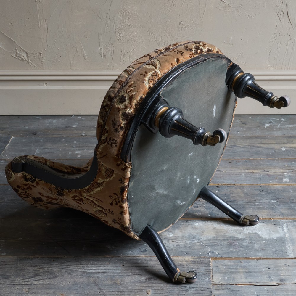 A Victorian low-seated tub chair upholstered in brown patterned floral velvet with ebonised turned legs, gilt accents, and brass castors. View VIII