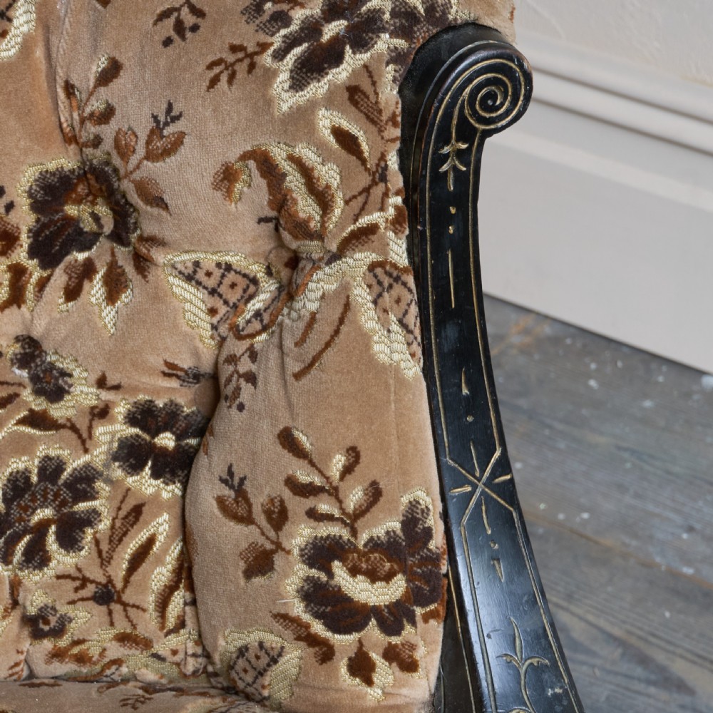 A Victorian low-seated tub chair upholstered in brown patterned floral velvet with ebonised turned legs, gilt accents, and brass castors. View XI